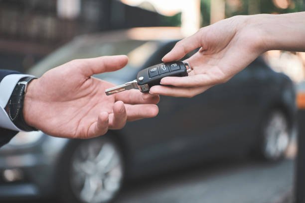 Car dealership Young man receiving car key from saleswoman